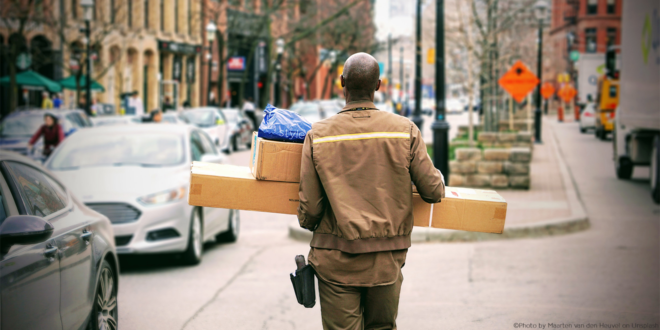Lieferant läuft durch die Straßen mit Paket und Kleidungsstück
