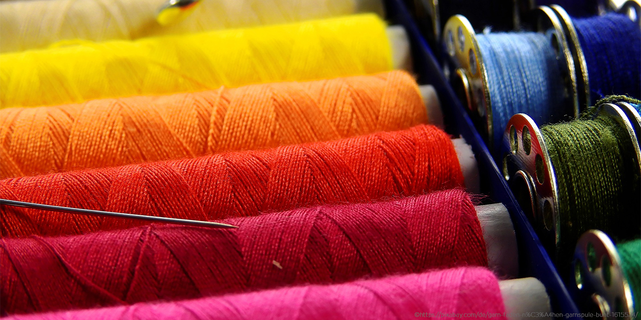 Bunte Fäden und Nadel zum Kleidungsstück flicken