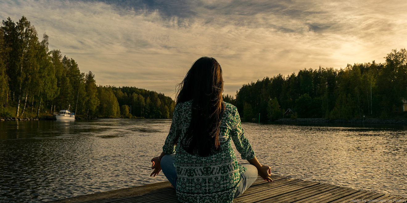 Frau entspannt beim Yoga vor einem Sonnenuntergang