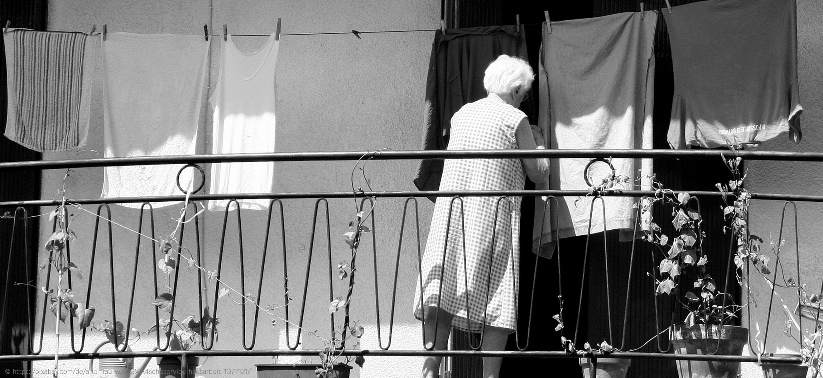Oma hängt T-Shirts und Unterhemden auf die Wäscheleine