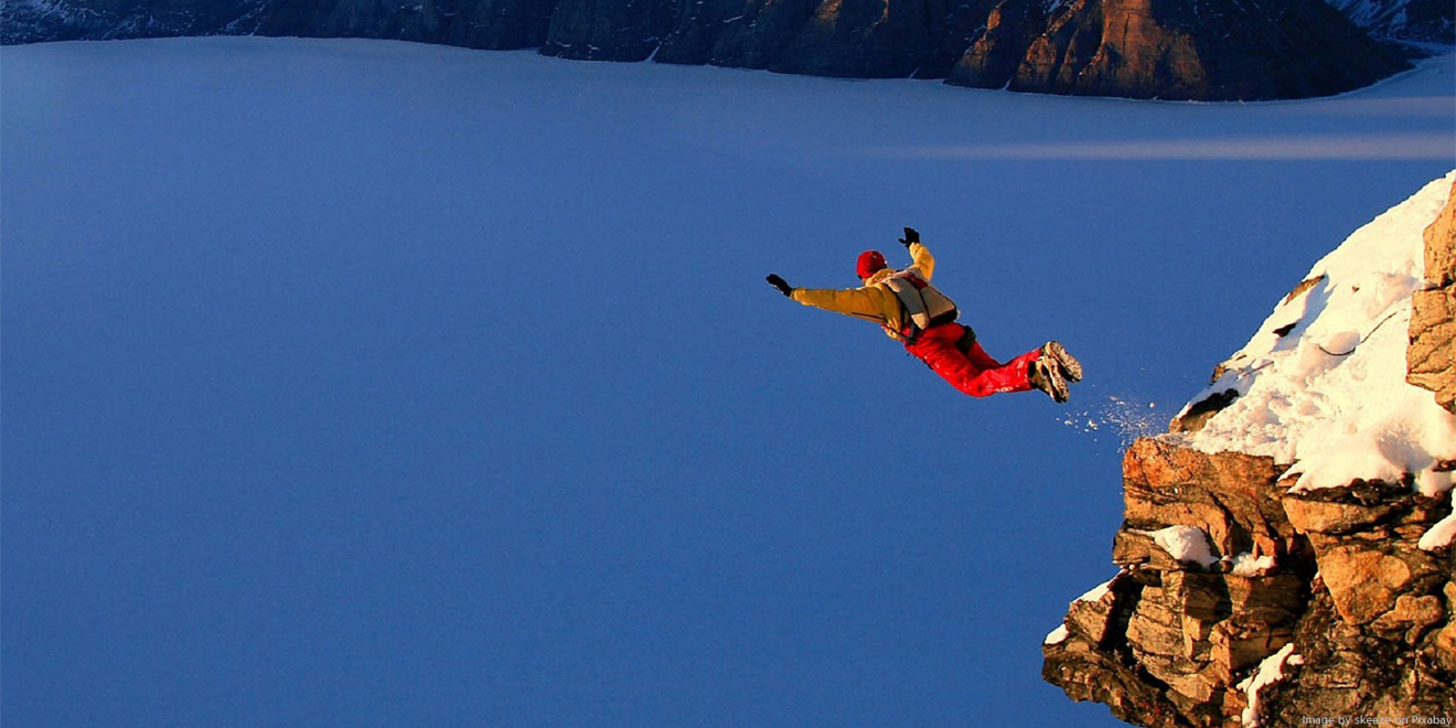 Base Jumper stürzt sich vom Felsen in die Tiefe, mit einem Fallschirm auf den Rücken. 