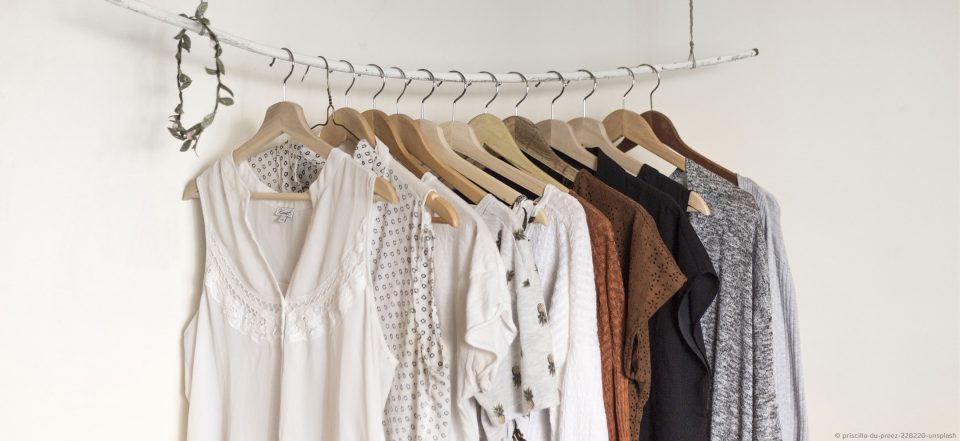 Ein Kleiderschrank mit Kleidungsstücken von weiß über Erdtöne bis Schwarz.