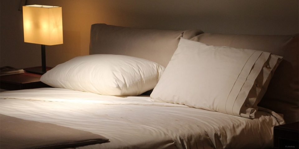 Leeres weißes Bett mit Lampe und Buch zum schlafen und lesen