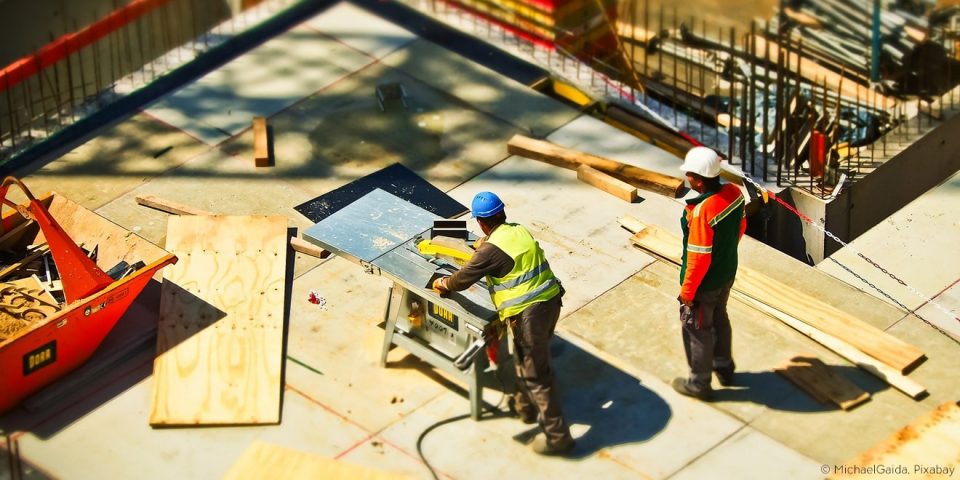 Bauarbeiter arbeiten am Bau mit schweren Materialien und Geräten.