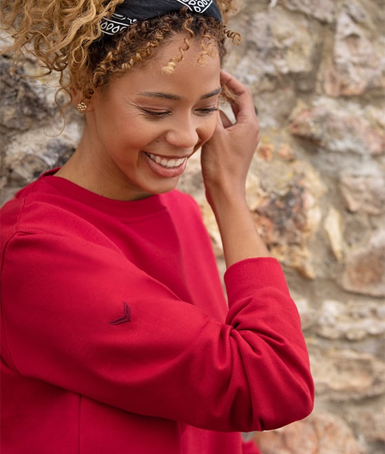 Dame mit rotem Basic-Sweatshirt von TRIGEMA. Das Sweatshirt ist ein Teil der Geschichte des Pullovers.