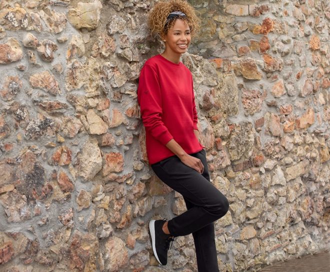 Dame in Sweatshirt und passender Jogginghose vor einer Steinwand. Ein perfektes Beispiel dafür, wie alltagstaugliche Loungewear aussehen kann. 