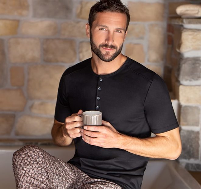 Alltagstaugliche Loungewear lässt sich in jeder Situation tragen. Beispielsweise wie dieser Herr in einem Basic Oberteil und einer locker, leichten Hose mit Allover-Print.