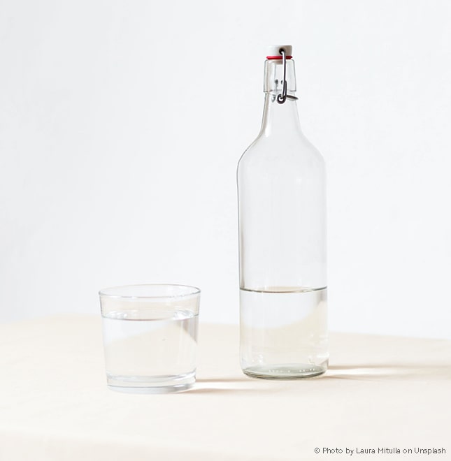 Wasserflasche aus Glas kann oft verwendet werden und reduziert den PET-Verbrauch drastisch.